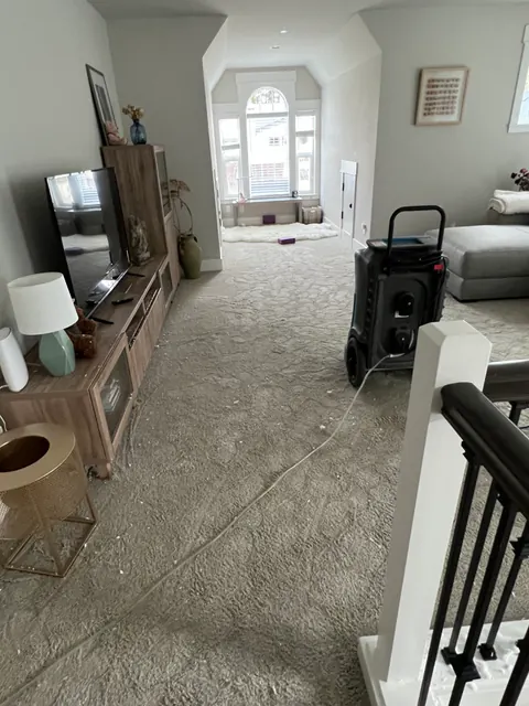 Second-floor family room with a dehumidifier running on wet carpet