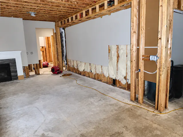 Flood-cut drywall with insulation exposed and air movers in the great room